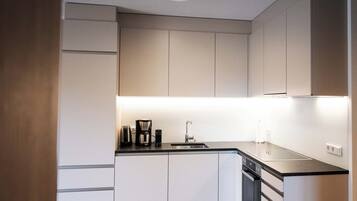 A modern kitchen with a built-in dishwasher, a coffee maker, and a sink.
