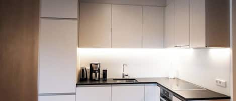 Una cocina moderna con lavavajillas integrado, cafetera y fregadero.
