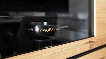 A black object with a mountain design on a stand inside a wooden-framed glass enclosure.