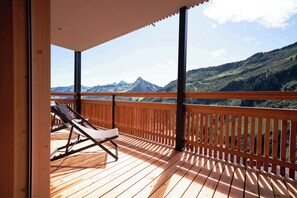 A wooden deck with a single lounge chair, overlooking a mountainous landscape. - Landhaus Damüls (Damüls)