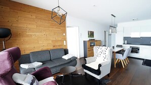 Un salon moderne avec un canapé gris, un fauteuil à motifs et un tapis noir.