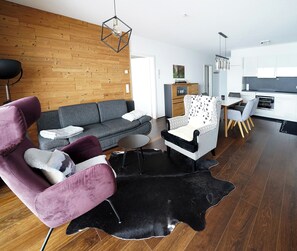 Una sala de estar moderna con un sofá gris, un sillón estampado y un tapete negro.