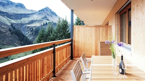 Une terrasse en bois avec une table et des chaises, offrant une vue sur un paysage montagneux.