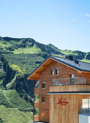 Un hotel con fachada de madera y balcón con vistas a un paisaje montañoso.