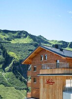 Un hotel con fachada de madera y balcón con vistas a un paisaje montañoso.