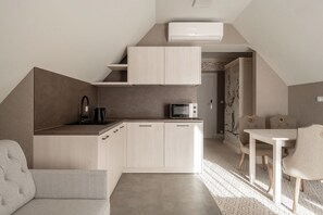 A compact kitchen with a microwave, kettle, and a small dining area with a table and chairs. - Aries Residence Witkac (Zakopane)
