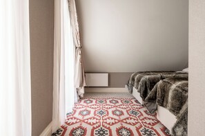 A bedroom with a patterned rug, a fur throw, and a white bedside table. - Aries Residence Witkac (Zakopane)