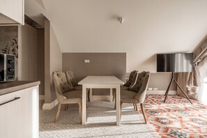 A room with a dining table and chairs, a flat-screen TV, and a patterned carpet. - Aries Residence Witkac (Zakopane)