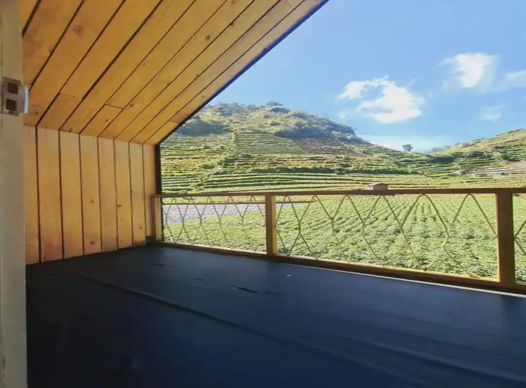 A room with a wooden ceiling and a view of terraced fields.