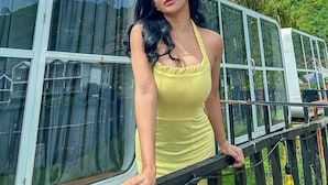 Una persona de pie junto a una estructura de vidrio con barandilla de metal.