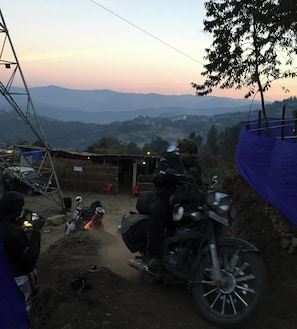 Una moto aparcada en un camí de terra amb un paisatge de muntanyes al fons.
