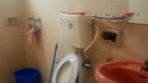A bathroom with a toilet, sink, and a window.