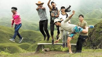 A group of people in a natural outdoor setting with a hilly landscape in the background.
