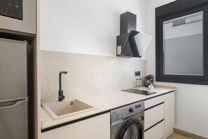 Eine kleine Küche mit Spüle, Geschirrspüler und Fenster.