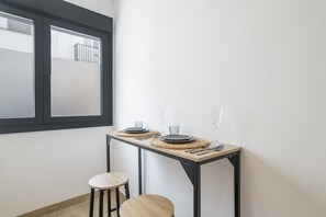 Ein Essbereich mit einem Tisch für zwei Personen, einem Fenster und einem kleinen Hocker.