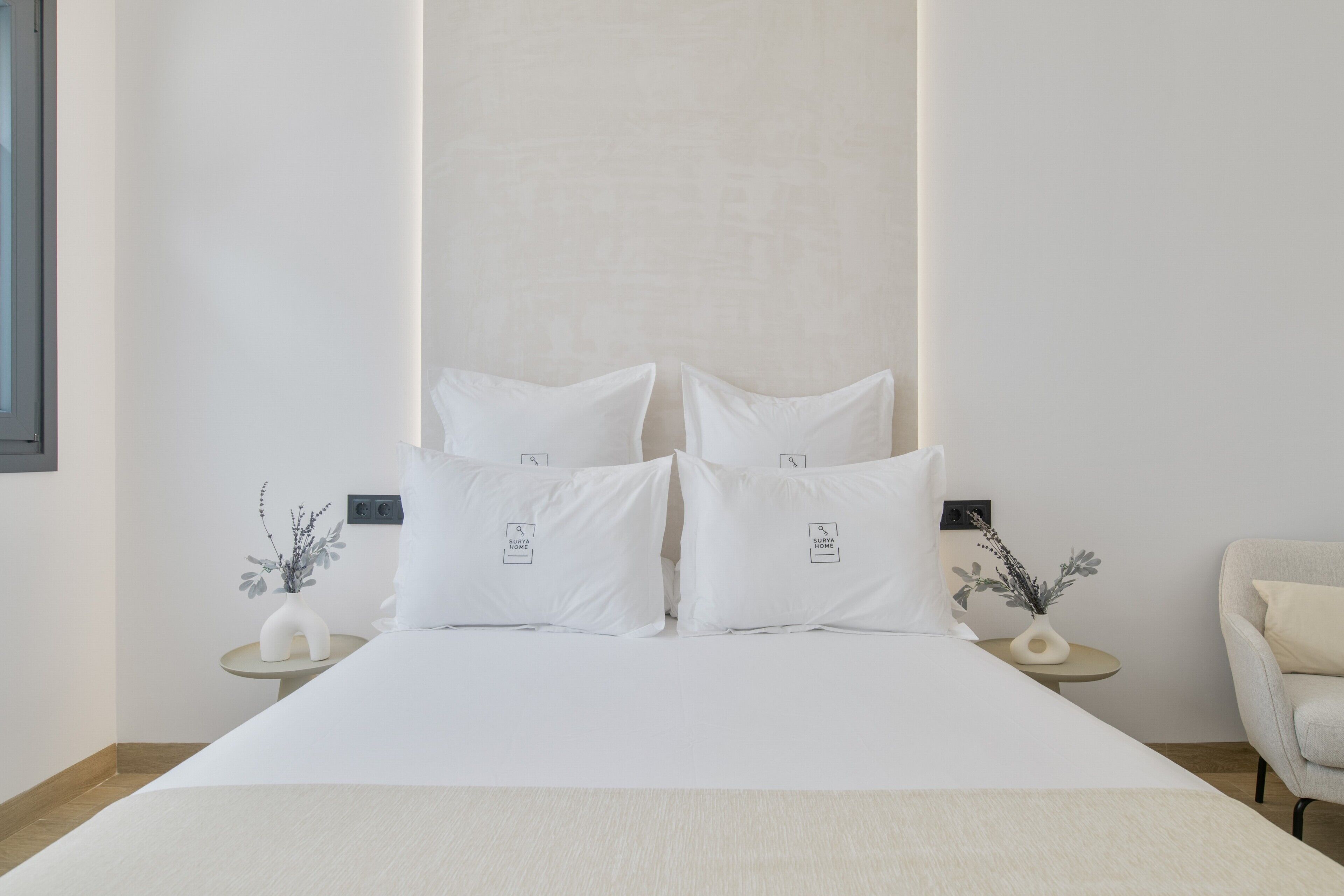 A neatly arranged bedroom with a bed, two bedside tables, and a chair.