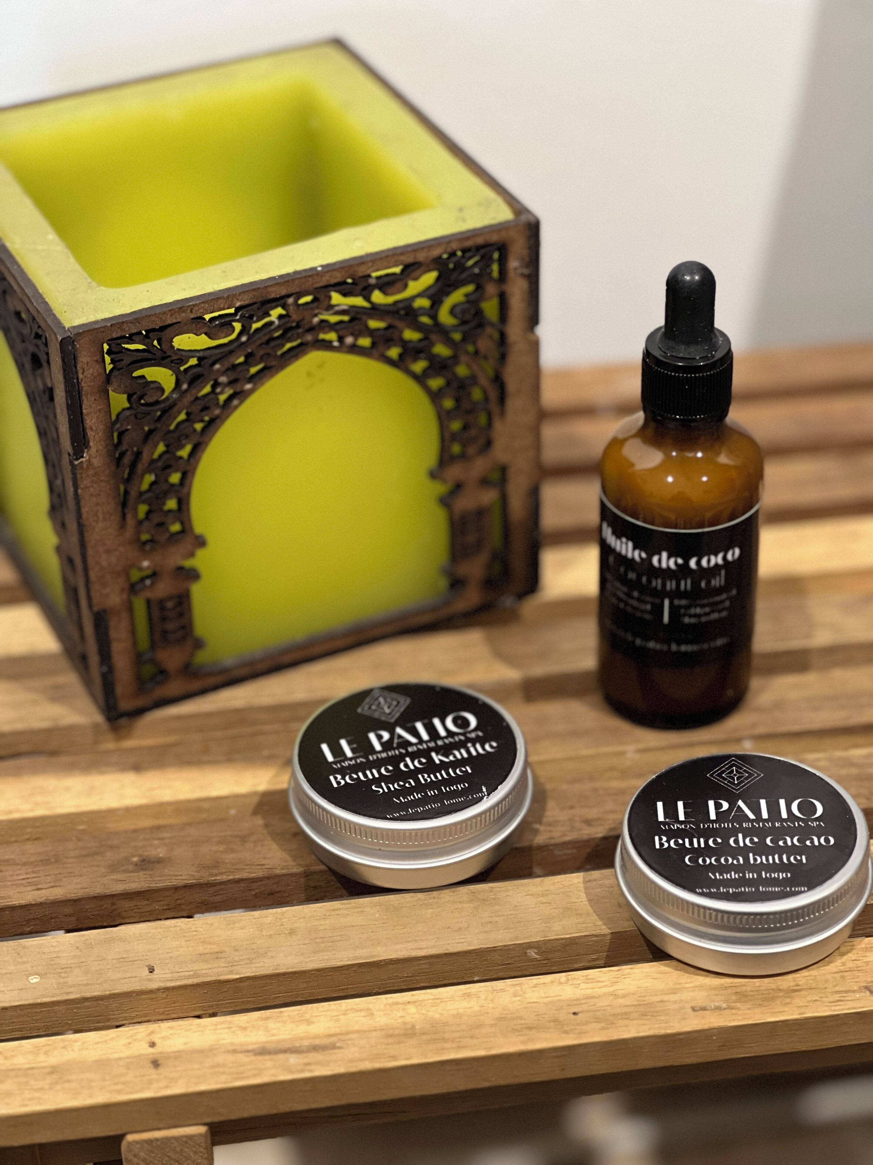 Two containers of Le Patio cocoa butter and a bottle of cocoa oil on a wooden surface.