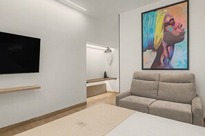 A modern living room with a flat-screen TV, a grey sofa, a wooden shelf, and a colorful abstract painting on the wall. - Estudio '102' con Wi-Fi y Aire Acondicionado (Conil de la Frontera)