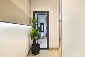 Ein Flur mit einem Blumentopf, einer Tür und Blick in einen anderen Raum.