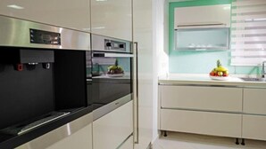 Eine moderne Küche mit Edelstahlgeräten, einer schwarzen Arbeitsplatte und einer grünen Akzentwand.