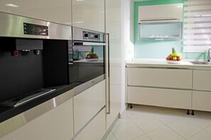 Eine moderne Küche mit Edelstahlgeräten, einer schwarzen Arbeitsplatte und einer grünen Akzentwand.