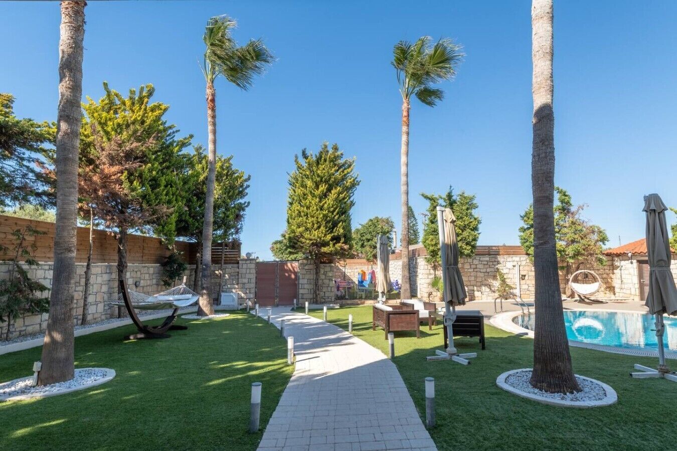 A poolside area with palm trees, a pathway, and a hammock.