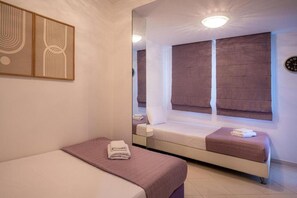 Ein Schlafzimmer mit einem Bett, einem Fenster mit Jalousien, einem Nachttisch und einem Spiegel.