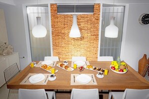 A dining area with a wooden table set for breakfast, including plates, cutlery, and a fruit bowl. - Serenity Bliss Villa (Gouves)