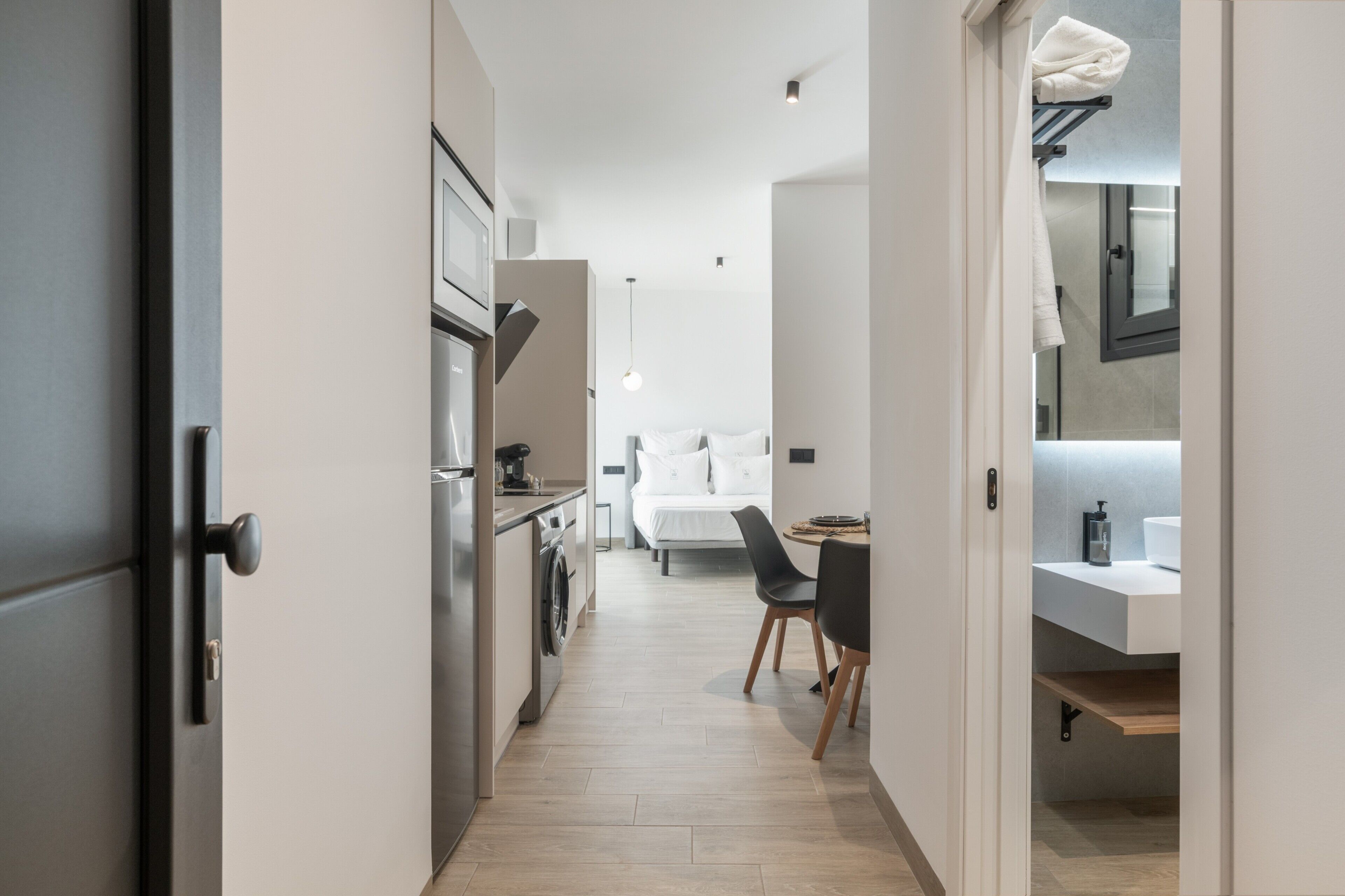 Una cocina moderna con comedor, cama y baño con lavamanos y espejo.