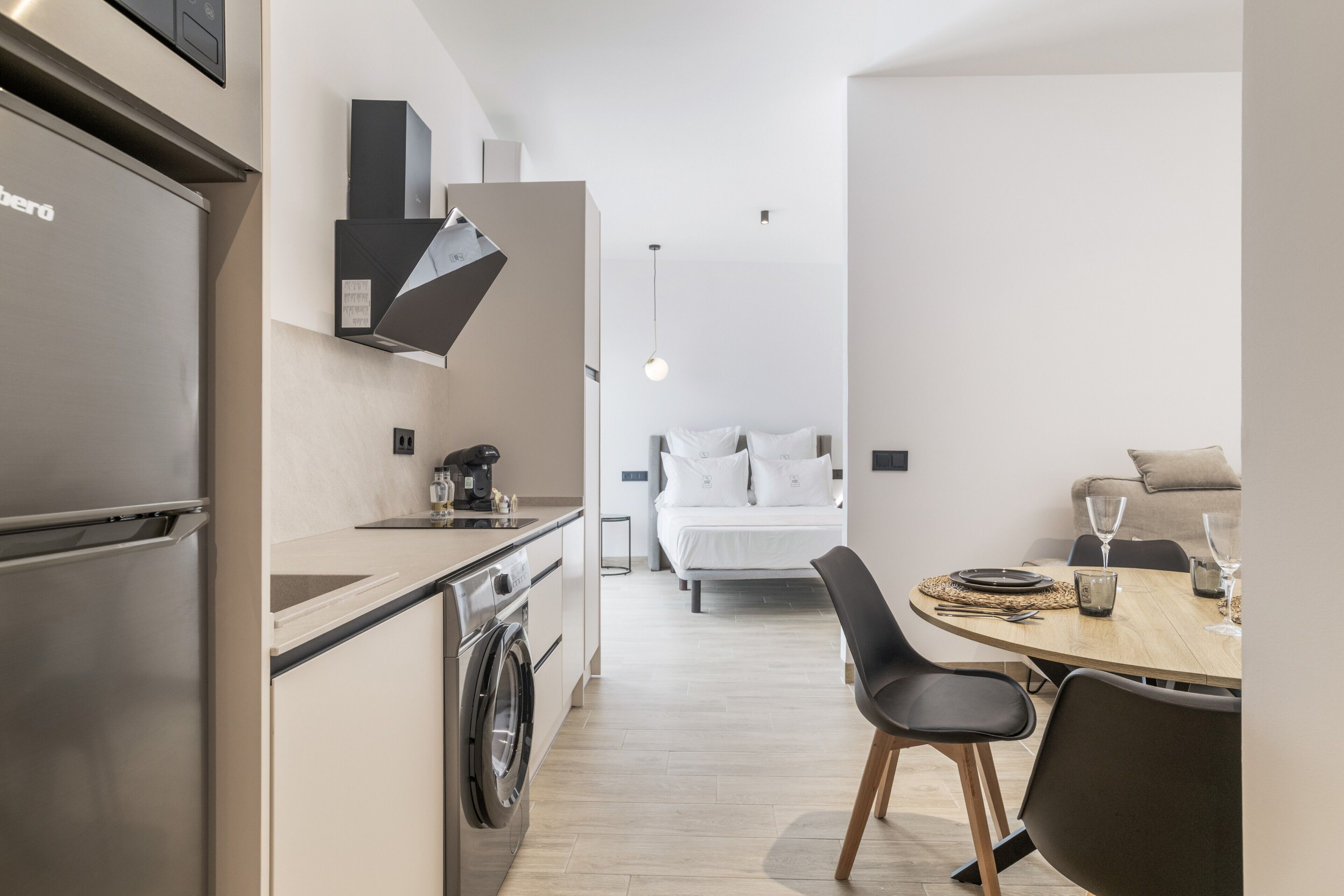 Habitación de hotel pequeña con kitchenette, cama y comedor.