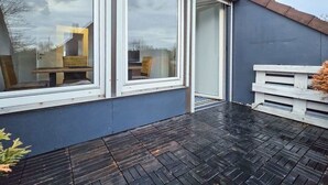 A modern building with large windows, a dark tiled patio, and a white bench. - Alpha Apartments: Grand Space | 6 Beds & Parking (Datteln)