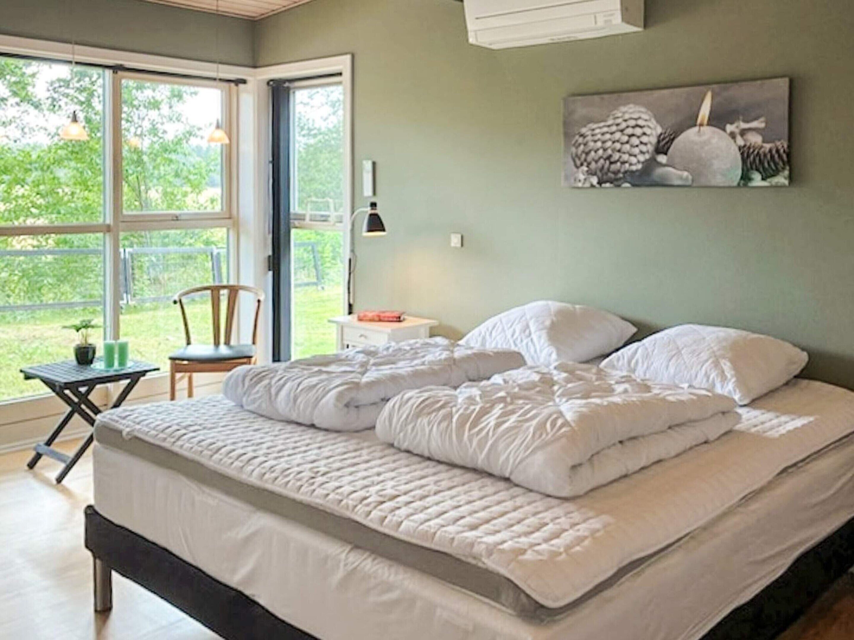 A bedroom with a bed, a chair, a table, and a window.