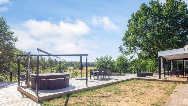 A wooden deck with a hot tub, outdoor seating, and a covered area. - 4 Star Holiday Home in Ans By (Ans)