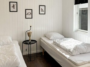 A bedroom with two beds, a small table with a vase, and framed pictures on the wall. - 4 Star Holiday Home in Ans By (Ans)