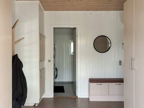 A hallway with a coat rack, a bench, and a door leading to a laundry area. - 4 Star Holiday Home in Ans By (Ans)
