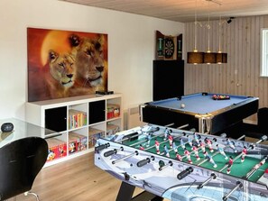 Ein Raum mit einem Kicker, einer Dartscheibe und einem Bücherregal mit Büchern und Spielen.