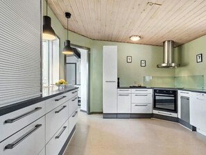 A modern kitchen with white cabinetry, a stainless steel range hood, and a black countertop. - 4 Star Holiday Home in Ans By (Ans)