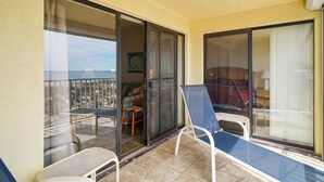 Un balcó amb porta corredissa de vidre, una cadira i vista a la zona de seients exterior.