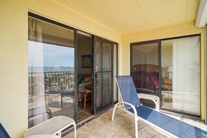 A balcony with a sliding glass door, a chair, and a view of the outdoor seating area. - Includes Xplorie Activities and Linens. Anchorage II 305 on the oceanfront at 130th Street! (Ocean City)