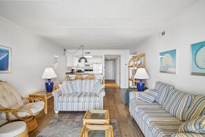A modern living room with a sofa, armchair, and a dining area with a table and chairs. - Includes Xplorie Activities and Linens. Anchorage II 305 on the oceanfront at 130th Street! (Ocean City)