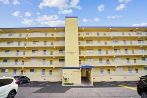 A multi-story hotel with a central elevator shaft, balconies on each floor, and a parking lot with cars. - Includes Xplorie Activities and Linens. Anchorage II 305 on the oceanfront at 130th Street! (Ocean City)