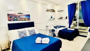 Habitación de hotel con cama, escritorio, silla, mesita y ventana con cortinas.