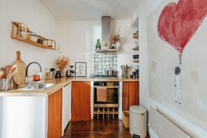 A kitchen with wooden cabinets, a built-in oven, a sink, and a stove. - Guéthary: Between the Ocean and the Village, Terraces, and Gardens (Guéthary)