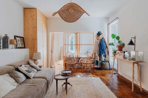 A cozy living room with a sofa, a coffee table, and a dining area with chairs and a table. - Guéthary: Between the Ocean and the Village, Terraces, and Gardens (Guéthary)