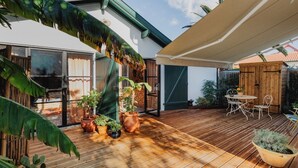 A wooden deck with potted plants, a table with chairs, and a covered area. - Guéthary: Between the Ocean and the Village, Terraces, and Gardens (Guéthary)