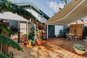 A wooden deck with potted plants, a table with chairs, and a covered area. - Guéthary: Between the Ocean and the Village, Terraces, and Gardens (Guéthary)