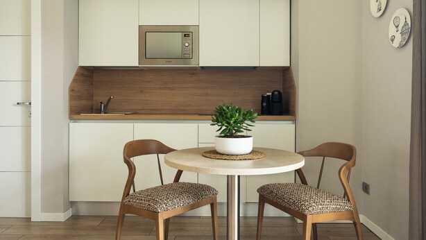A compact kitchen with a microwave, two chairs, a small table, and a potted plant. - Rota Suites (Rota D'Imagna)