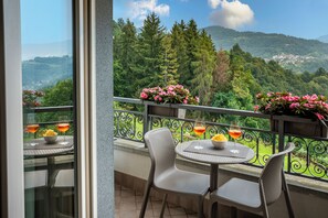Ein Balkon mit Tisch und Stühlen, einer Geländer und Blick auf eine gebirgige Landschaft.