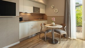 A modern kitchen with a built-in microwave, a coffee machine, and a dining area with a table and chairs. - Rota Suites (Rota D'Imagna)
