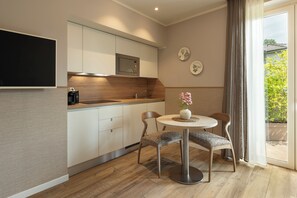 Eine moderne Küche mit eingebauter Mikrowelle, einer Kaffeemaschine und einem Essbereich mit Tisch und Stühlen.